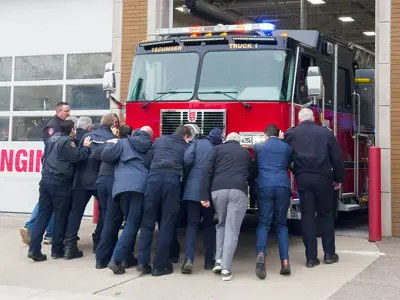 Firefighters and members of Council pushing in the new firetruck into the Fire Station